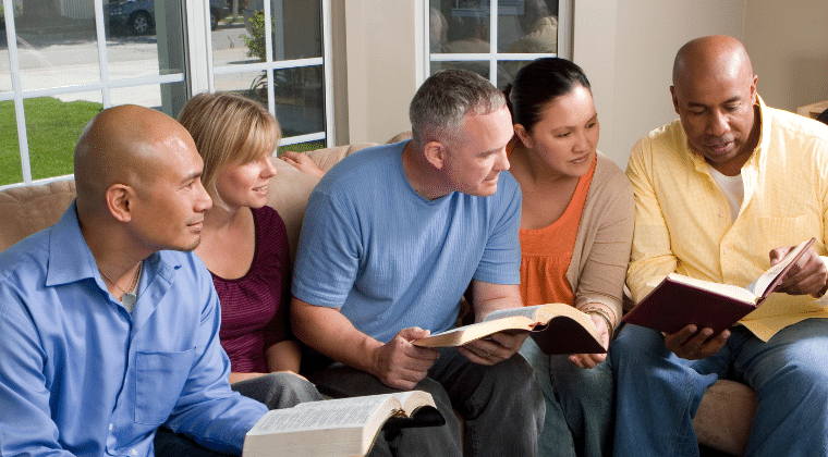 diverse group of people sitting in a group with bible and engaging.