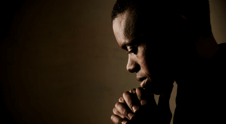 Person with head bowed and hands folder on chin.